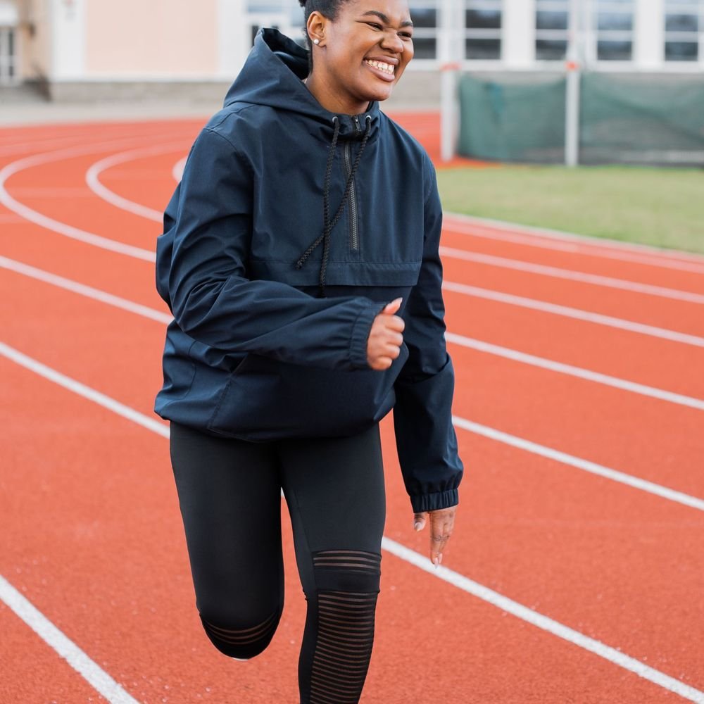 Sportive souriante en tenue de course sur une piste d'athlétisme
